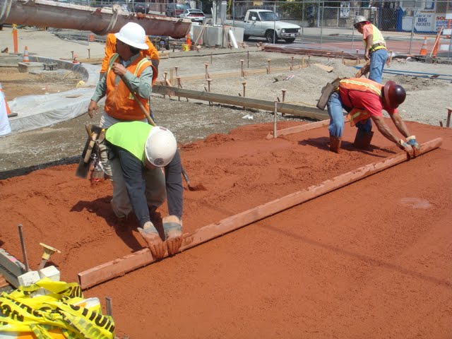 The concrete contractors are screeding the concrete. The concrete pigment is Brick Red by Davis Colors