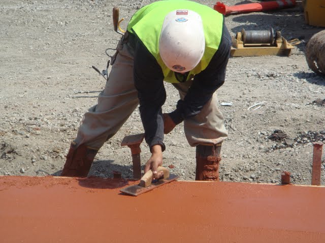 The concrete contractor is finishing the colored concrete. The concrete pigment is Brick Red by Davis Colors