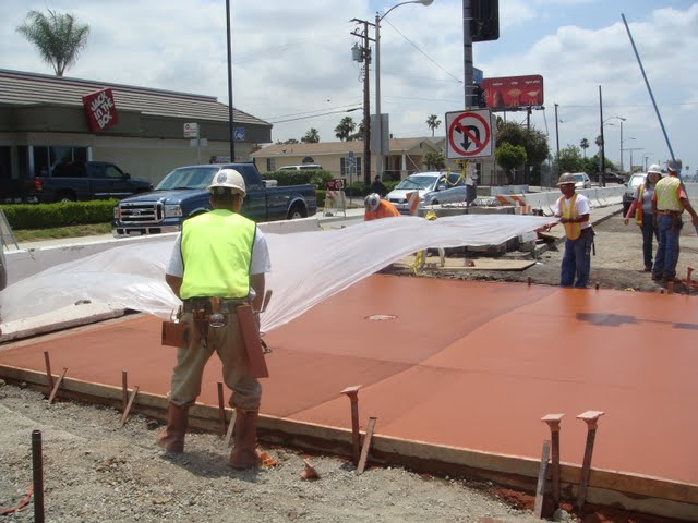 The visqueen plastic sheet is being placed on top of the colored concrete to get ready for the stamping process. Concrete pigment is the Brick Red product from Davis Colors