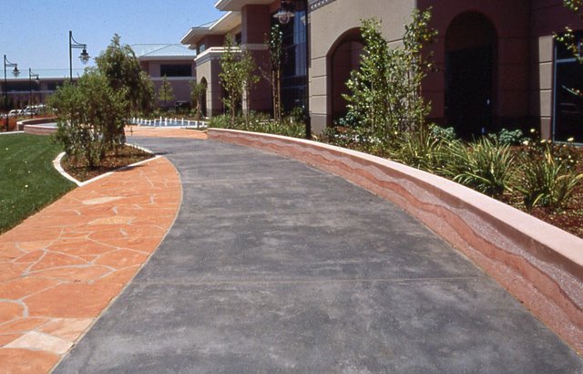 Cisco Systems' Campus - The walkway was colored with Davis Colors' Dark Gray (860) concrete color.  The walls were colored with Davis Colors Brick Red and 1117 at 5 lbs per sack of cement.  The walls all had varying degrees of exposure created by sand blasting the surface.   The concrete had varying levels of concrete colors to achieve the random look of a washed out terrain.