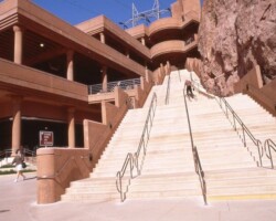 The Hoover Dam parking structure is a cast-in-place structure using pan slab forming. It is tucked inside a steep ravine that has been partially blasted out to provide enough room for the structural footprint. Stretching 540 ft. in length in a stepped down configuration, the structure is 165 ft. wide and three levels high at the rear, 215 ft. wide and five levels high in front. The structure’s concrete is integrally colored to blend in with the surroundings canyon rock. To learn more about the Hoover Dam visit the Bureau of Reclamation website – www.usbr.gov/lc/hooverdam/index or Wikipedia at http://en.wikipedia.org/wiki/Boulder_Canyon_Project#Planning_and_agreements .
