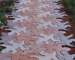 Gecko Stone™ © 1997 John AugustAdmittedly inspired by artist M. C. Escher, August's copyrighted design is uniquely different - transforming a derivative image into a practical art form through a process known as tessellation or tiling - a combination of both art and geometry. August has incorporated this technique into a series of truly interlocking pavers which require no additional borders to keep them from wandering off in your garden. To find learn more about John Austust's products visit his website at www.geckostone.com or call him at 888-976-1190. Photo is copyrighted by Geckostone - John August.